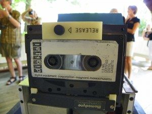 A cassette tape is on display in front of a group of people.