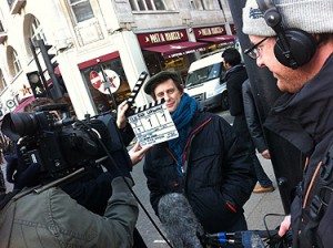A man holding a clapper board in front of a camera.