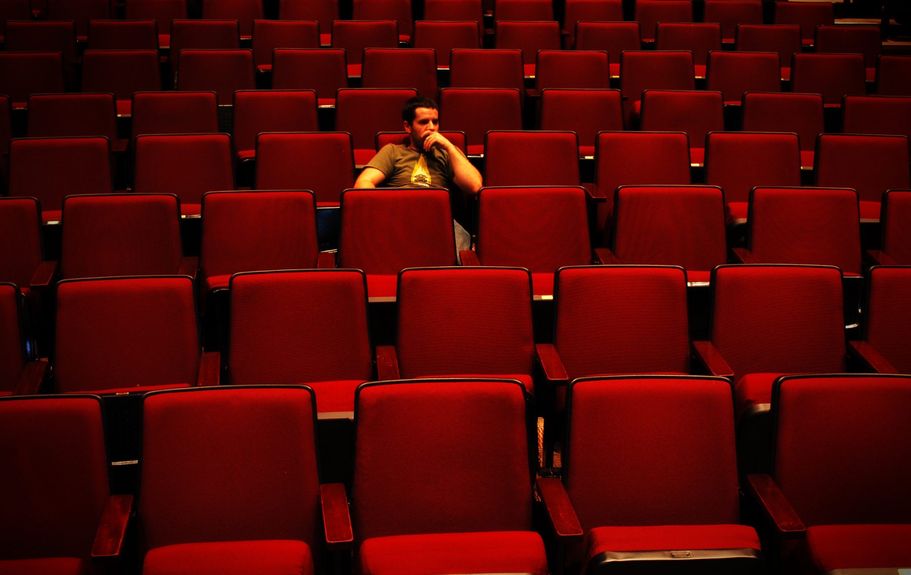 A person sitting in an empty auditorium.